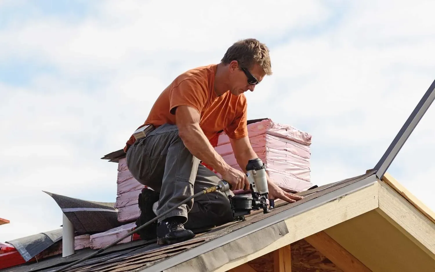 Man on roof peak nailing down standard looking shingles