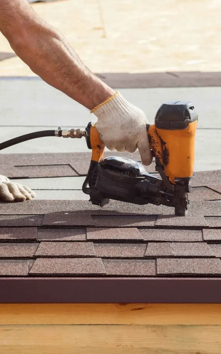 New_Image_Roof_worker using nail gun on shingles vertical