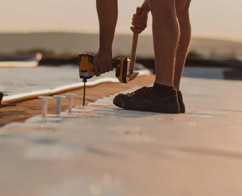 commercial roofer working on drilling material to roof